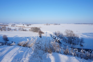 Baltic sea shore in winter. Steep descent to water against blue sky. Steep river bank. Sunny wintry landscape.
