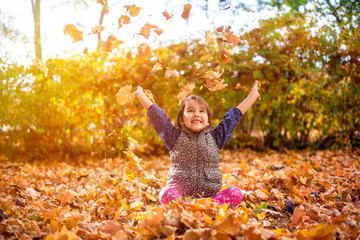 Little and beautiful girl enjoy autumn season and throw up leaves