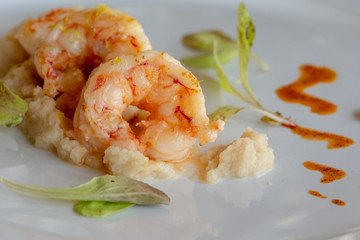 cooked shrimps on a white plate with tomato sauce on the side in a zigzag pattern