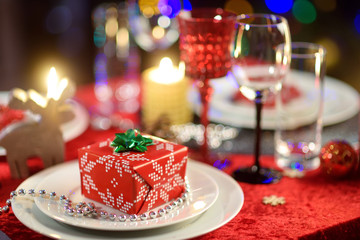 Beautiful table setting for Christmas party or New Year celebration at home. Cozy room with a fireplace and Christmas tree in a background.