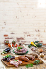 Selection of French Raw sausage with arugula leaves in a wooden board,vegetable on the table on old white cracked red brick wall background.