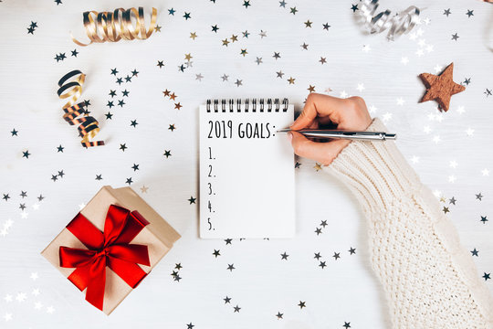 Holiday decorations and notebook with 2017 goals on white rustic table, flat lay style. Christmas planning concept.