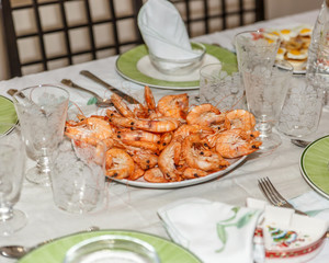 View of a prepared table with glasses, plates, napkins and a plate of prawns