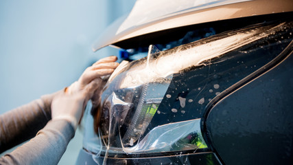 man glue a protection membrane on car headlight on carwash © Masson
