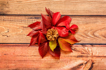 Pile of autumnal red leaves and cone on  wooden background