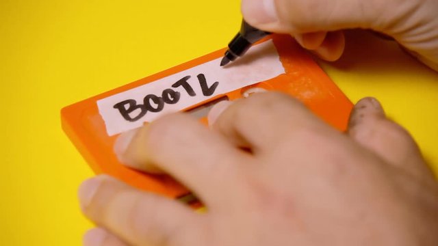 Writing the text Bootleg on the rough label of a vintage cassette tape (obsolete music technology). Colorful scene.
