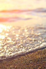 Wet sea sand on beach against background beautiful golden sunset. Close up sea sand on shore ocean during sunset.Landscape sunset sea coast. Golden wet sand sand on beach on a sunset background