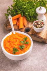 Bright tasty pureed carrot soup in clay bowl