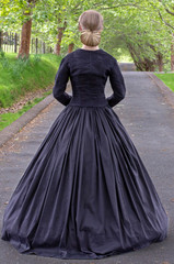 Fototapeta premium Victorian woman in black ensemble outdoors