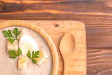 Tasty pureed mushroom soup in wooden bowl with ingredients