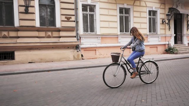 Young woman ride on retro bicycle on the autumn streets 