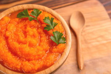Bright tasty pureed carrot soup in wooden bowl