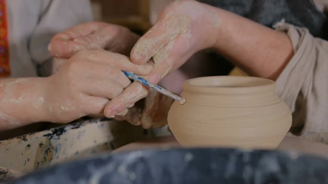 Pottery class and workshop: professional male potter working with kid and showing how to make ceramic wares in pottery studio. Handmade, education and study concept