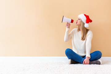 Young woman with santa hat holding a megaphone on a white carpet