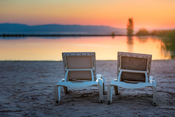 sunbeds together with sun umbrella on the beach in a sunset