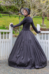 Fototapeta premium Victorian woman in black ensemble outdoors