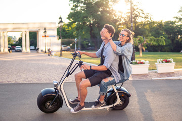 Lovely young couple driving electric bike. Modern city transportation