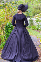 Fototapeta premium Victorian woman in black ensemble outdoors