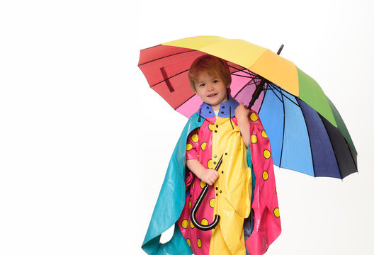 Cheerful boy in raincoat with colorful umbrella. Smiling little boy playing with umbrella and looking at camera. Smiling little boy wearing in fashionable seasonal clothes having Autumnal mood.