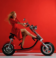 Fototapeta na wymiar Woman ride new electric car motorcycle bicycle scooter bike red dress surprised