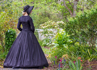 Fototapeta premium Victorian woman in black ensemble outdoors