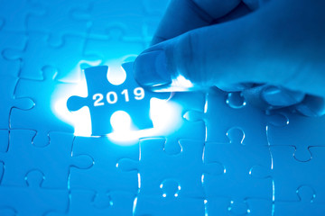 2019 word on jigsaw puzzle. Businessman hands holding white puzzle business concept. Business, finance, salary, crisis, and development concept. New year planing.