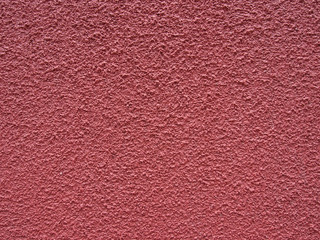 A faded red dark pink rough textured painted concrete wall surface