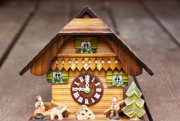 Wooden wall clock in the form of a house stand on brown boards with perspective. Design element.
