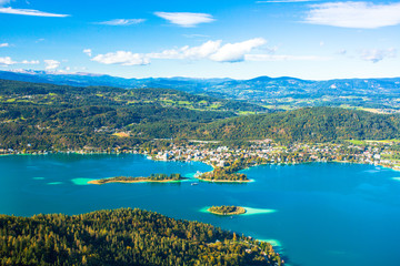 Obraz premium Worthersee is the largest lake of province Carinthia in Austria. The lake attracts visitors to swim and to ice skate when freezes over in winter. Sandbanks appear light green in the blue lake water.