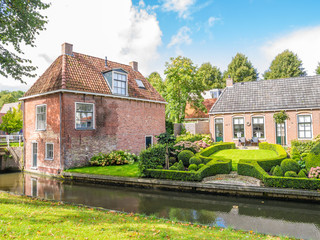 Fototapeta na wymiar Streetscene of canal with waterfront houses and gardens in old town of Dokkum, Friesland, Netherlands