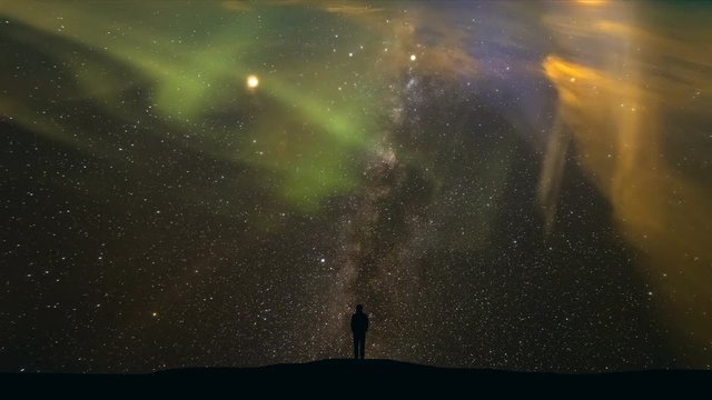 The man standing on a background of starry sky with a northern light. time lapse