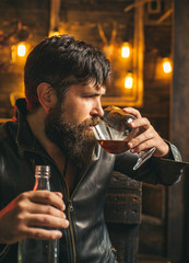 Man drinks brandy or whiskey. Bearded man wearing jacket and drinking whiskey brandy or cognac. Serious man having alcohol and nicotine addiction. Stop alcohol and smoking addiction.