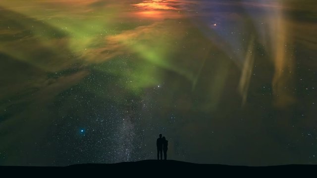 The couple standing on a background of starry sky with a northern light