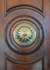 Fototapeta na wymiar Detail of a golden knob and an ancient wooden portal.