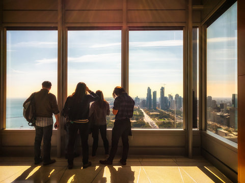 Group Of Visitors Looking Out Of A Skyscraper Window. Chicago Skyline.