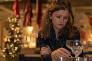 young woman sitting in a cozy living room, having in the background a beautiful Christmas tree 