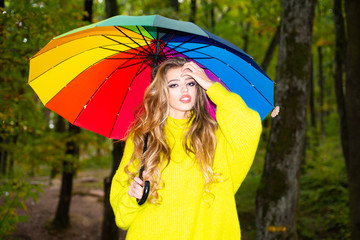 Autumn woman walking in the Park and enjoying the beautiful autumn nature. Pretty woman having fun at the park and smiling. Beautiful Autumn Woman with colorful umbrella on Fall Nature Background.