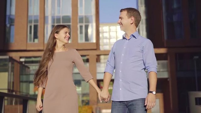 Cute couple walking around in city holding hands, laughing and talking.