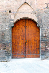 European style wooden doors with arch in a brick wall