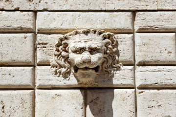 Stone lion carving detail on a wall of white bricks