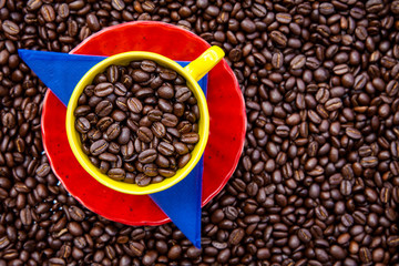 Cup filled with Colombian coffee beans and the colors of the Colombian flag over a background of roasted coffee beans