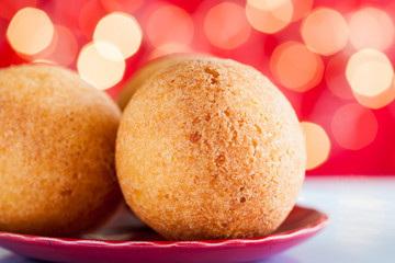 Traditional Colombian bunuelos (Deep Fried Cheese Bread) on christmas red background