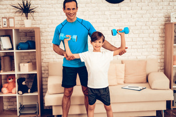 Fototapeta na wymiar Father Helping Little Boy with Dumbbells at Home.