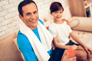 Father and Son on Sofa with Water Bottles in Hands