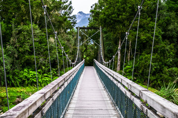 The wooden swing bridge in the green nature.