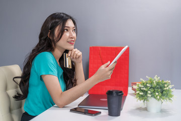 woman thiking and using digital tablet for online shopping with credit card