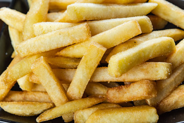 French fries close-up in black plate with sauce.