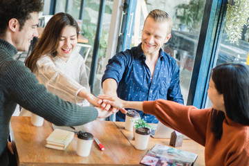 Young businessman and woman meeting in café and stack up for new target