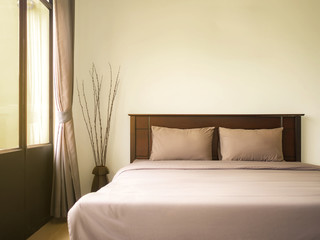 Empty double wooden bed in luxury and natural style bedroom is simple decorated with two pillow. Copy space.