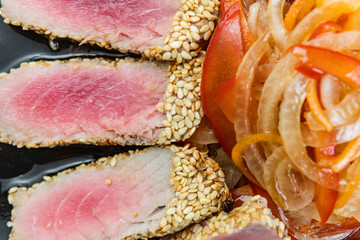 Close Up Still Life of Roasted Tuna Steaks Crusted with Herbs and Sesame Seeds on Dark Gray Surface